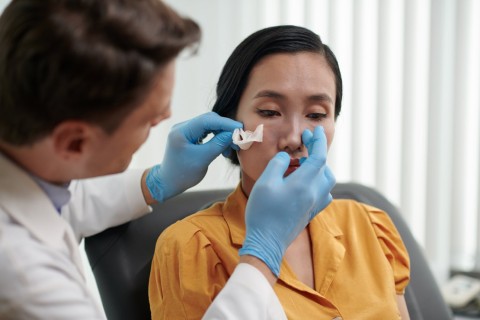 a woman being checked post rhinoplasty process by a professional